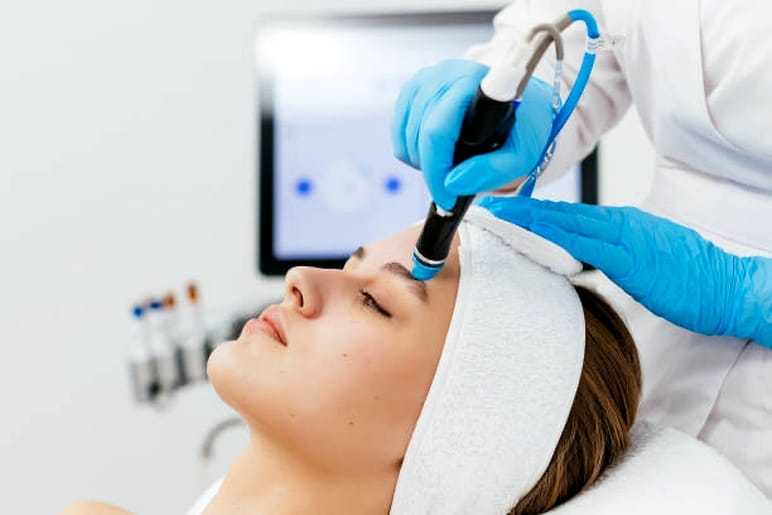 Facial treatment with dermabrasion device in a spa.
